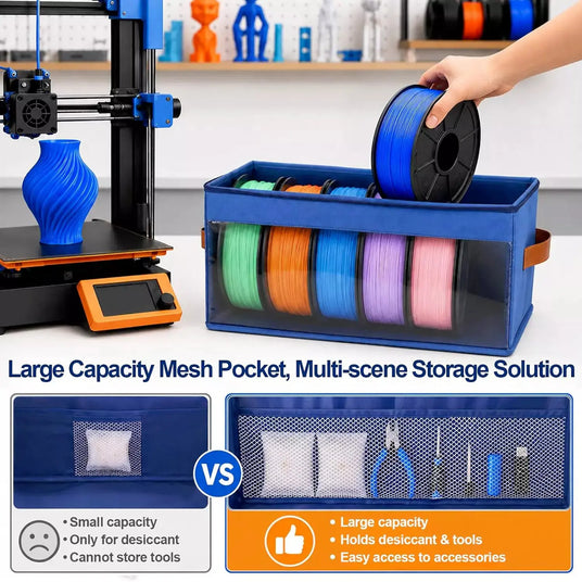 Blue filament storage bin next to a 3D printer, demonstrating a large internal mesh pocket designed for desiccant packs, pliers, and printing accessories.
